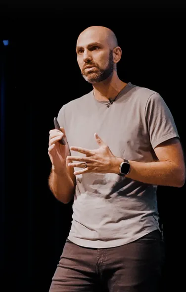 A close-up of a speaker in a gray shirt presenting onstage.